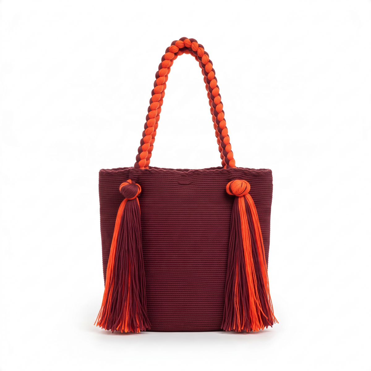 Bolso Wayúu LamuJoyas de algodón tejido a mano en color burdeos con asas trenzadas y borlas decorativas naranjas.