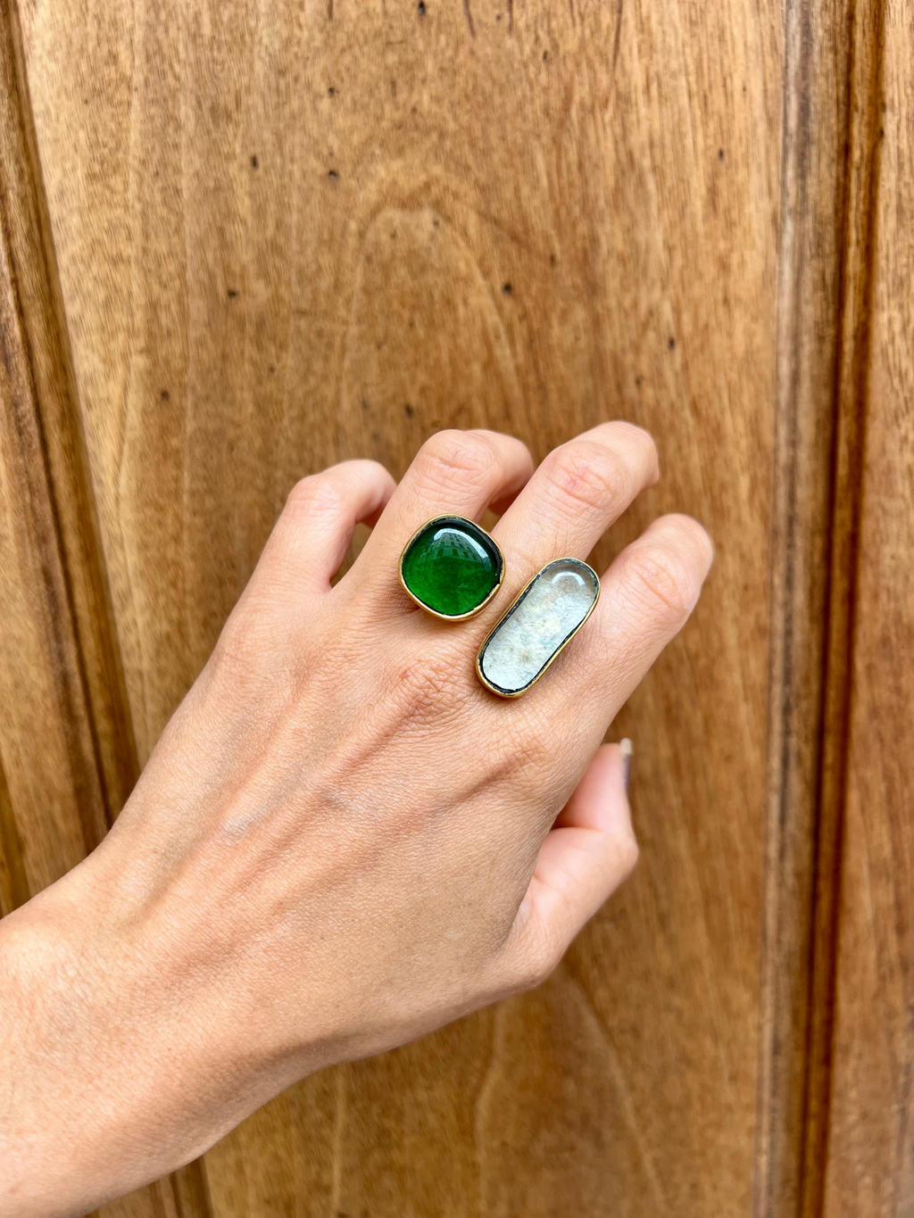 Anillo Zafir de LamuJoyas hecho a mano con latón reciclado y vidrio en tonos verde y turquesa sobre fondo de madera.