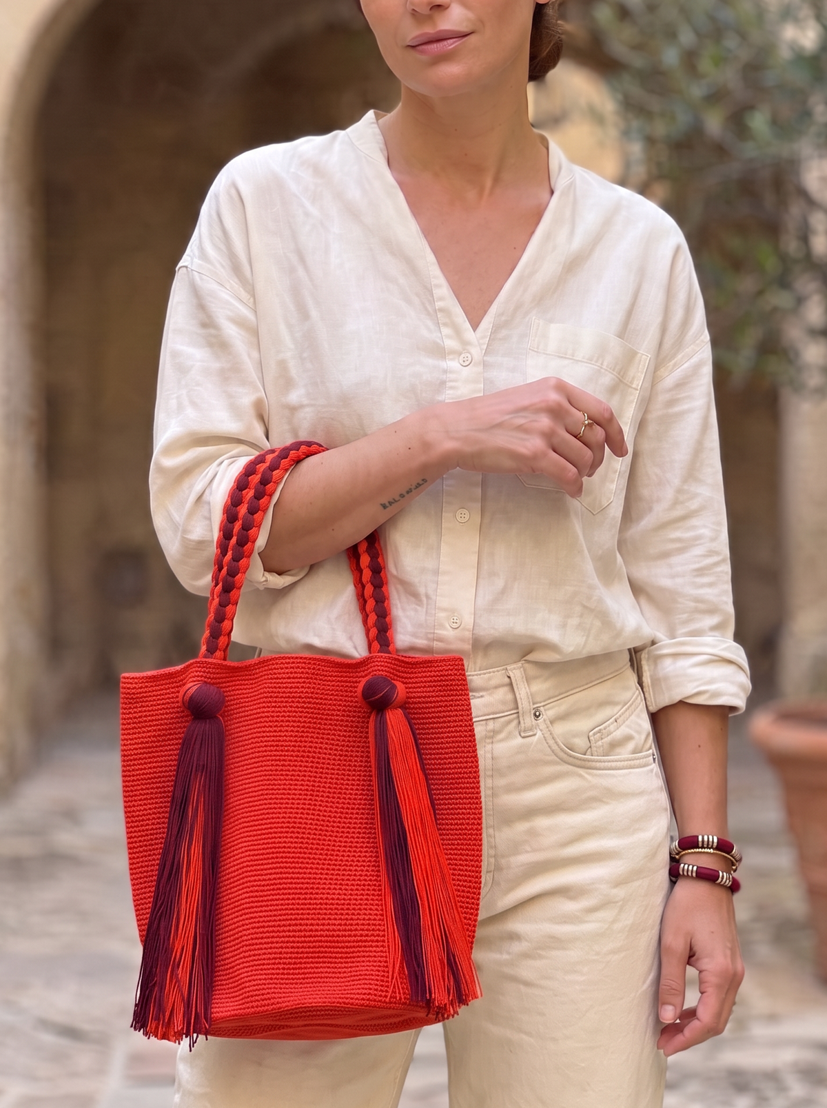 Bolso Wayúu LamuJoyas tejido a mano en algodón rojo con asas trenzadas y borlas decorativas, estilo artesanal.