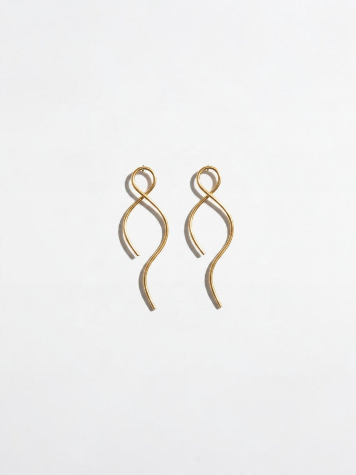 Pendientes Siri de LamuJoyas, diseño artesanal en latón dorado con forma ondulada y elegante estilo minimalista.